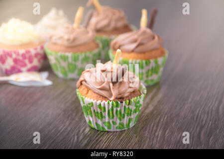 Chocolate cupcakes on wooden table background. Birthday celebration. Green stick Stock Photo
