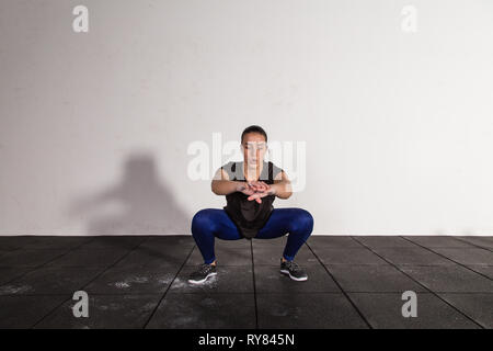 athletic young concentrated lady in sportswear doing squats in gym Stock Photo
