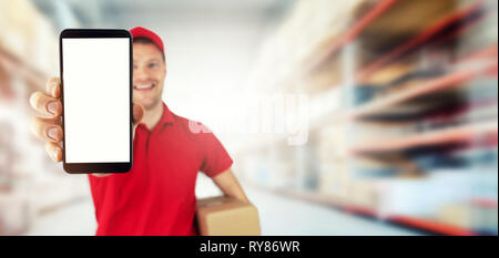 young smiling delivery service courier showing blank smart phone at warehouse. copy space Stock Photo