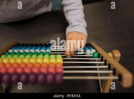 Cropped hand of girl using abacus on table at home Stock Photo