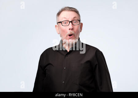 Senior man in black suit with amazed face as if he is so a great sale price. Stock Photo