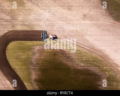 Aerial view of the tractor in the field, agricultural field work. Tractor cultivating field, aerial view. Stock Photo