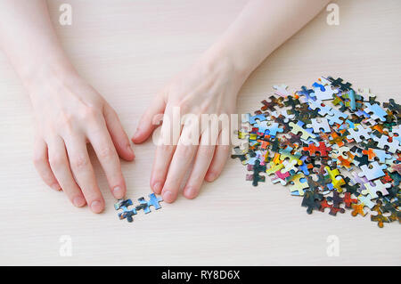 Caucasian girl collects puzzles on the table. View from above. Stock Photo