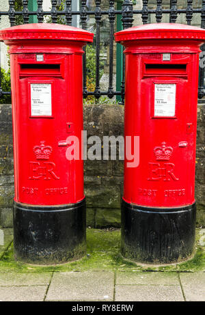 Two Red Cylindrical Pillar Boxes side by side on the High Street in Chipping Sodbury, South Gloucestershire, England, UK Stock Photo