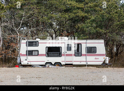 old camper sitting in dirt with trees behind Stock Photo