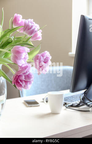 Working space and a bouquet of pink tulips in a vase Stock Photo