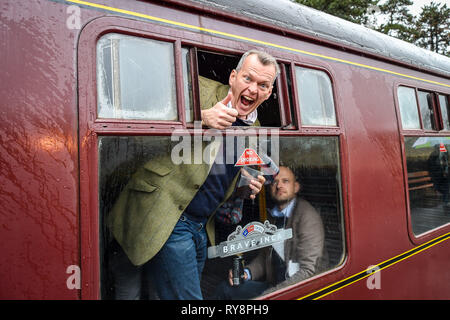 People heading for the races at Cheltenham peek out from their period carriage as they arrive at Cheltenham racecourse on the Gloucestershire Warwickshire Steam Railway from Toddington, where a special heritage steam express train service is taking race goers to Cheltenham. Stock Photo