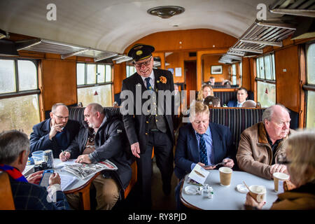 People heading for the races at Cheltenham relax in a period carriage on the Gloucestershire Warwickshire Steam Railway from Toddington, where a special heritage steam express train service is taking race goers to Cheltenham. Stock Photo