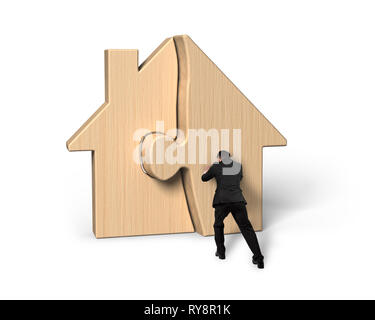 Businessman pushing assembling wooden house puzzles, isolated on white background. Stock Photo