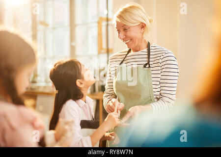 Portrait of smiling art teacher helping Asian girl in pottery class, copy space Stock Photo