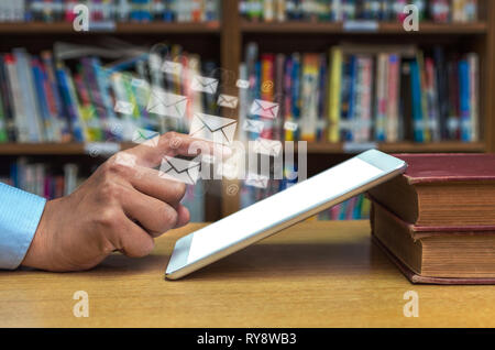 Finger pointing on the screen of tablet computer over the wood table in library, Education Technology concept Stock Photo