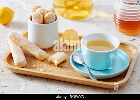 Sponge finger biscuits served with a cup of tea on wooden tray. Stock Photo