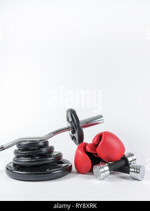Gym gears. Weight plates, curl bar, boxing gloves and two dumbbells in a heap. Place for own text / copy space. Stock Photo