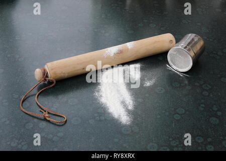 Wooden rolling pin, flour and flour shaker on a kitchen worktop Stock Photo