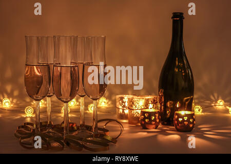 Cozy evening with glasses of champagne. For celebrations and special moments. Warm decoration light, candles and bottle in background. Stock Photo