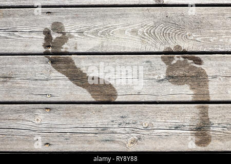 Wet footprints on a wooden jetty / bridge. Concept for swimming / bath, summer holidays / vacation, fun in the sun, etc. Fullscreen texture. Stock Photo