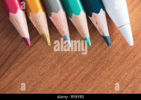 Apple Pencil 2015 1st generation for iPad Pro and traditional coloured pencils on wooden table Stock Photo