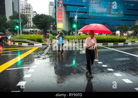 Elderly Singaporean man crossing Bukit Timah Road with Umbrella in the rain -  Sim Lim Square, Singapore Stock Photo