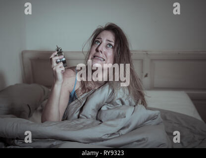 Sleepless and desperate beautiful caucasian woman awake at night not able to sleep, showing clock, feeling frustrated and worried suffering from insom Stock Photo
