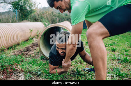 Participants obstacle course going through a pipe Stock Photo