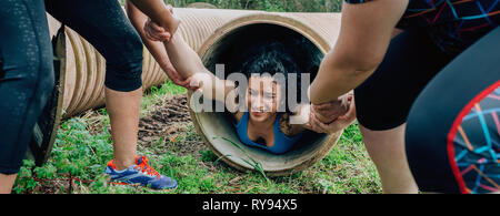 Participants obstacle course going through a pipe Stock Photo
