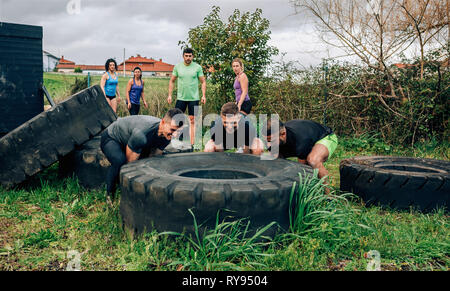 Participants in an obstacle course turning a wheel