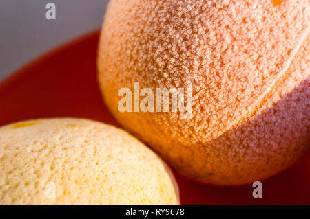 Frozen oranges and lemons on a red plate, covered in frost, illuminated by the sun Stock Photo