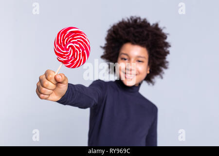 Resolute dark-haired joyful boy pulling out hand with candy in it Stock Photo