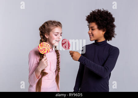 Smiling African American dark-haired boy proposing his red candy Stock Photo
