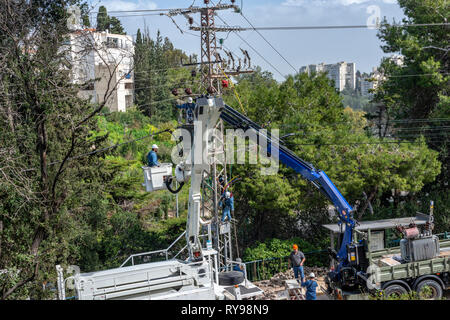 Haifa, Israel- February 26, 2019 :Electric company team working on a transmission tower using two truck lifts Stock Photo