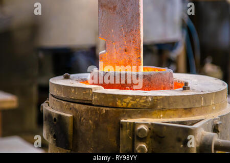 Closeup metal product melting in crucible on little foundry on blurred background Stock Photo