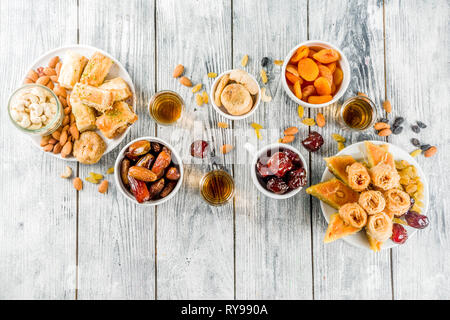 Set various Middle Eastern Arabian sweets - Turkish baklava, knafeh (kunaf), nuts, dried fruits and seeds. White wooden background, top view copy spac Stock Photo