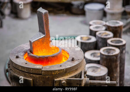 Closeup metal product melting in crucible on little foundry on blurred background Stock Photo