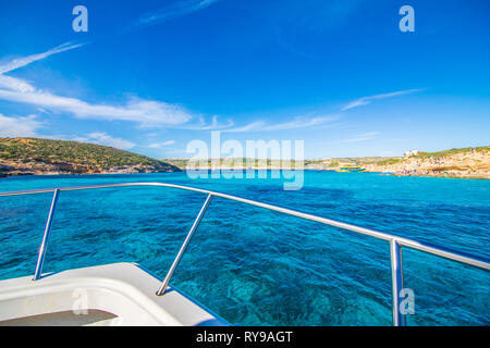 Comino, Malta - November, 2018: Tourists crowd at Blue Lagoon to enjoy the clear turquoise water on a sunny summer day with clear blue sky and boats Stock Photo