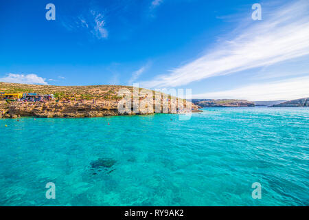 Comino, Malta - November, 2018: Tourists crowd at Blue Lagoon to enjoy the clear turquoise water on a sunny summer day with clear blue sky and boats Stock Photo