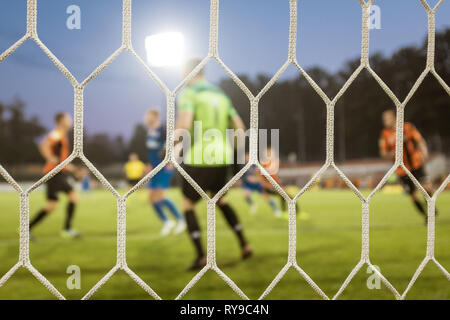 Net in a football goal with playrs and pitch in the background. Stock Photo