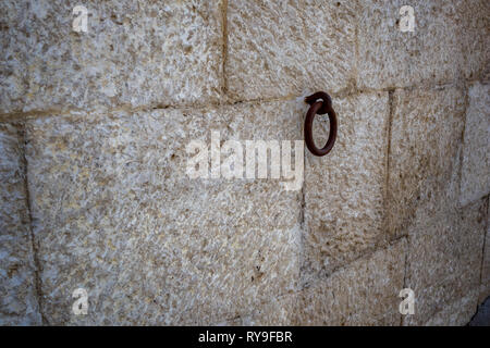 Rusty iron hoop hanging from carved stone wall in Matera, Basilicata region in Italy Stock Photo