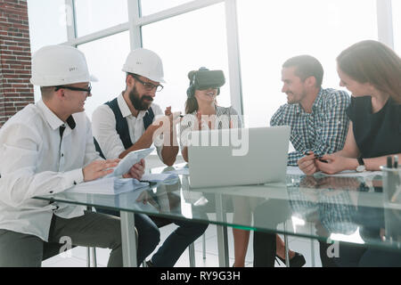 young designer in virtual reality glasses discussing her ideas with colleagues. Stock Photo