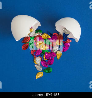 Colorful rainbow colored leaves coming out from broken egg minimal creative concept. Stock Photo