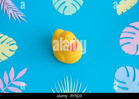 Rubber duck with colorful tropical leaves against pastel blue background minimal creative summer concept. Stock Photo