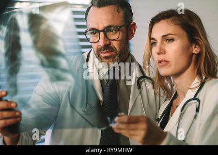 Skilled surgeon and doctor closely studying x-ray of chest of patient. Two doctors looking at patients chest x-ray scans in hospital. Stock Photo