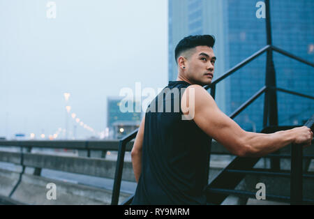 Man in walking up the stairs and looking away. Muscular man in sports clothing climbing up steps outdoors. Stock Photo