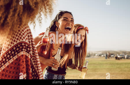 Three young women walking outdoors together and laughing. Group of multi-ethnic female friends having fun outdoors. Stock Photo