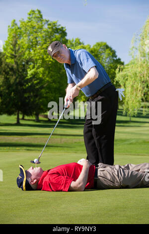 Mature male golfers Clowning Around on a Golf Green. USA Stock Photo