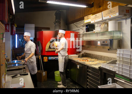 Italy pizza cooks; people working cooking pizza in a pizza restaurant, Caderzone village, Dolomites Italy Europe Stock Photo