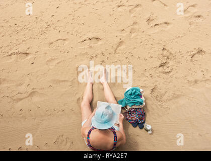 Woman reading book on beach. Stock Photo