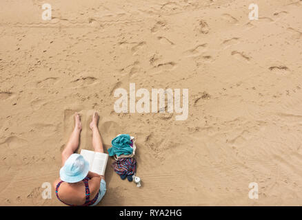 Woman reading book on beach. Stock Photo