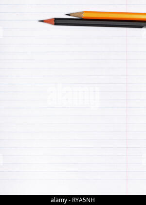 On a sheet of paper notebook with lines are black and yellow graphite pencils. Copy space. The concept of education. Flat lay Stock Photo