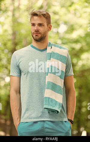 Taking minute break. Man athlete with towel after running outdoor, nature background. Athletic man relaxing break. Athlete with towel takes break duri Stock Photo