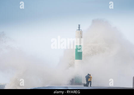 Aberystwyth, UK. 13th Mar, 2019. UK Weather: Young men take risks to get dramatic photographs of themselves close to the waves as gale force winds from Storm Gareth - the third named storm of 2019 - hit Aberystwyth on the Cardigan Bay coast, West Wales UK on Wednesday afternoon. Gusts of up to 70 or 80mph are forecast in exposed Northern regions, with the risk of serious damage to property and severe disruption to travel and power services Photo Credit: keith morris/Alamy Live News Stock Photo